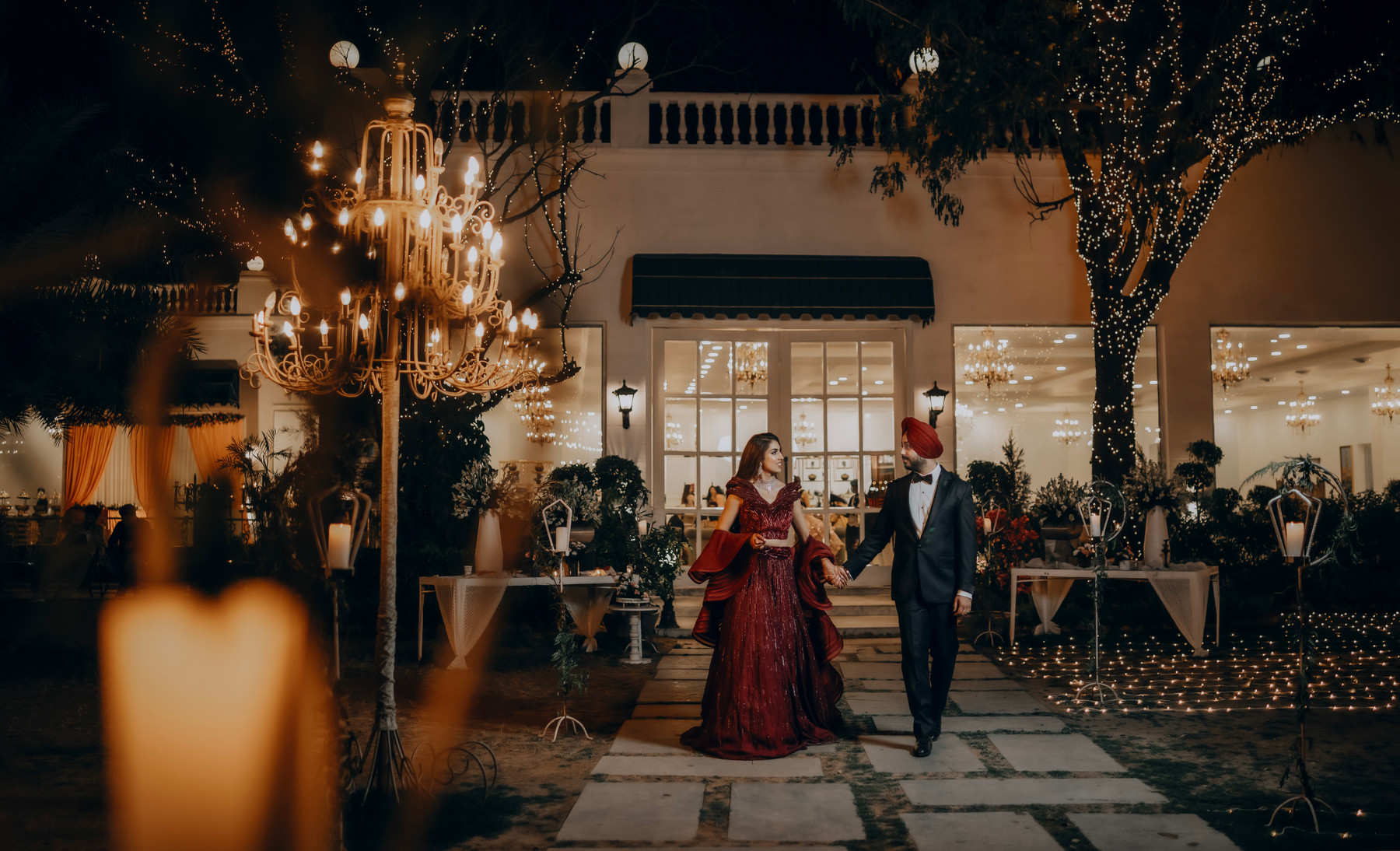 A couple holding hands in a candlelit garden