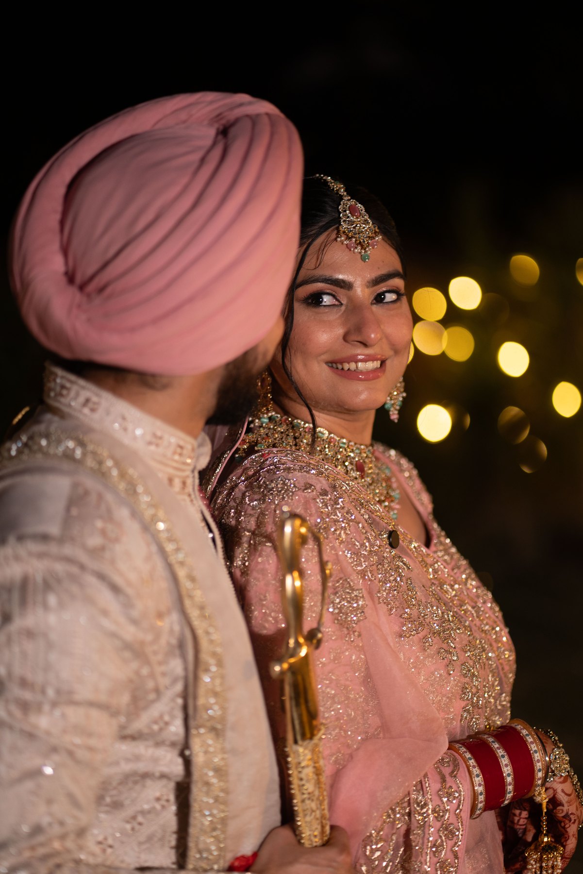 A smiling bride and groom in blush tones with warm evening lights