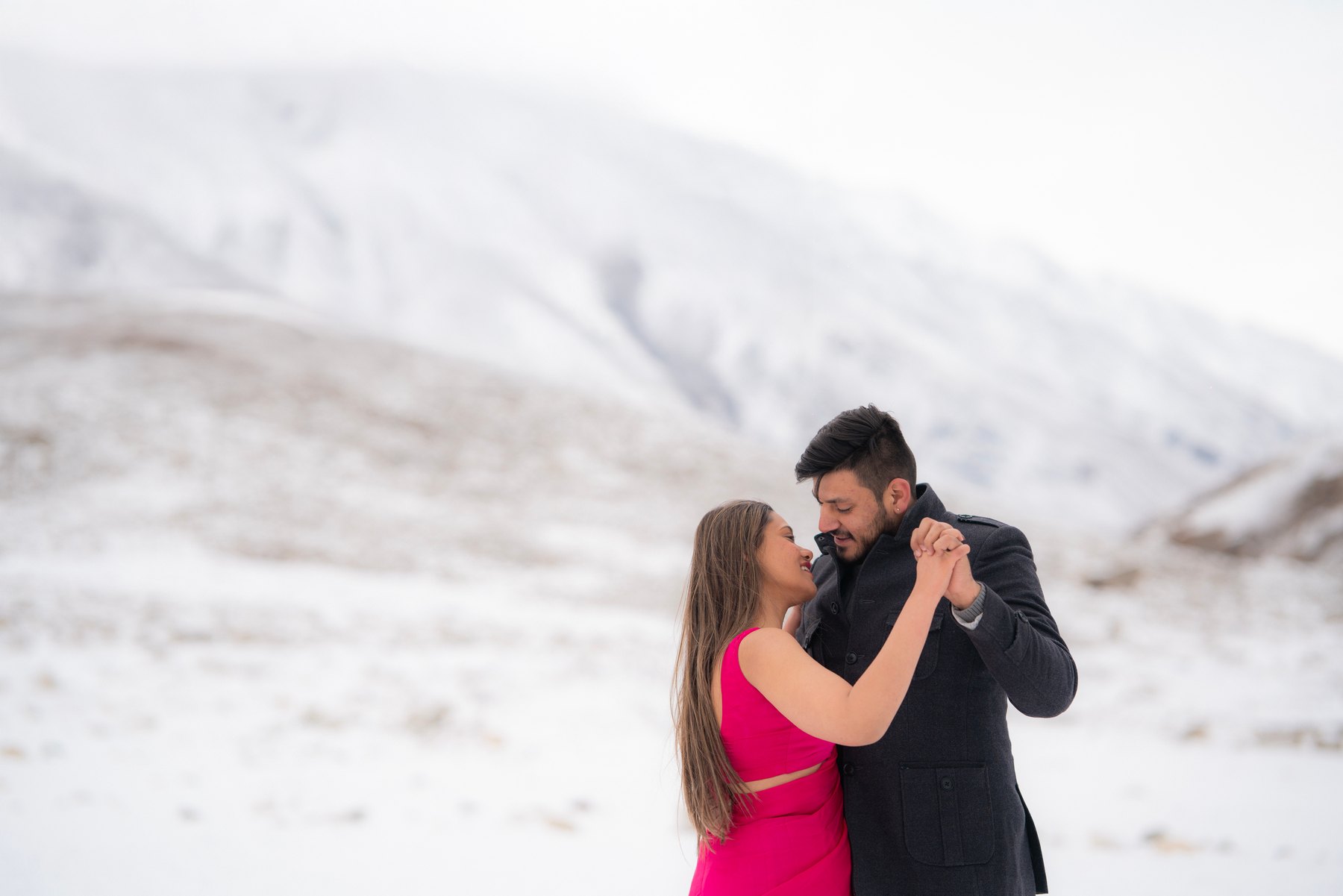 A couple dancing together against a snowy mountain backdrop