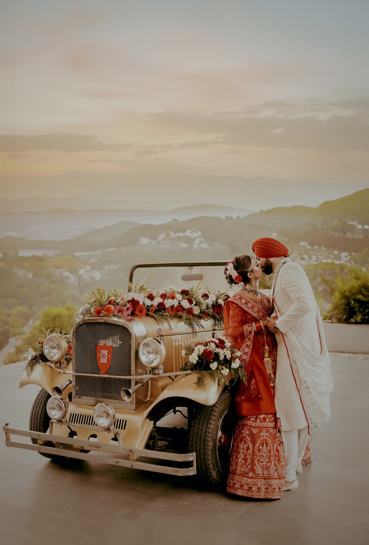 A couple beside a flower-decorated vintage wedding car